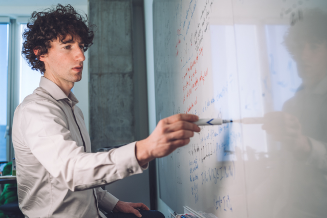 Guy Bresler writing on a whiteboard