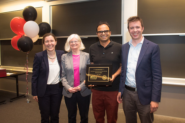 Devavrat Shah holding an award with EECS faculty