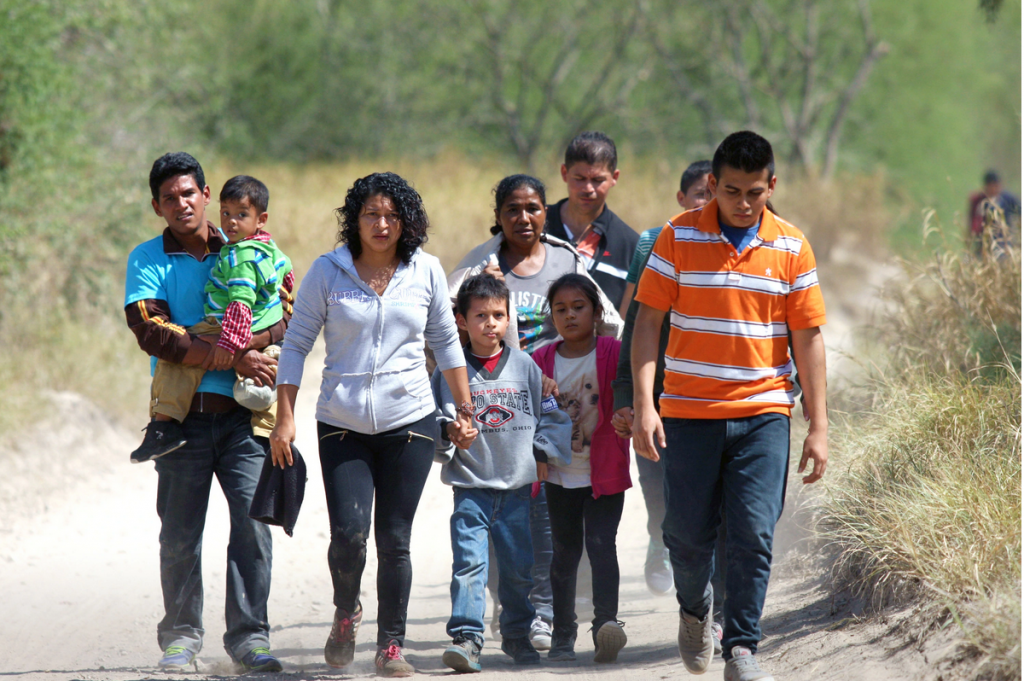 a group of Central Americans of various ages walking down a road in Texas