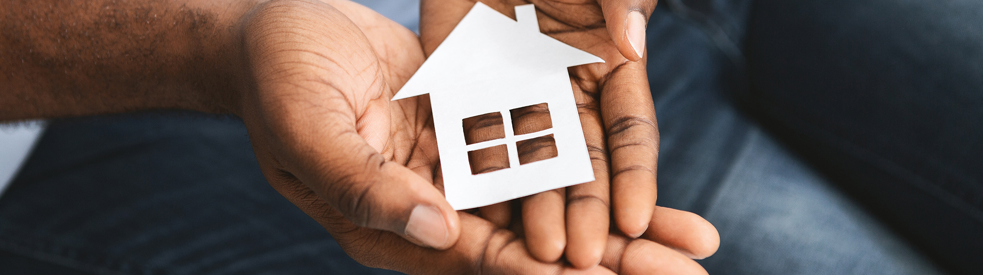 Close up of black couple hands holding wooden house