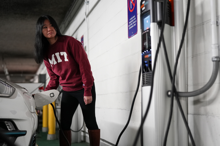 A person in an MIT sweatshirt plugs in an electric car