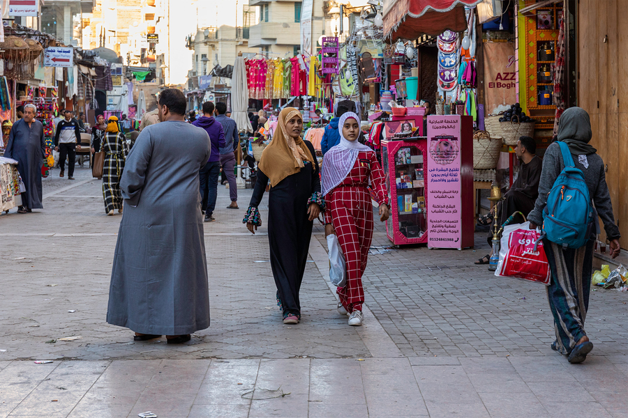 a pair of women walking down an egyptian city street