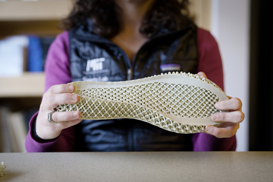 a researcher holding a 3-D-printed midsole, designed based on a model’s predictions