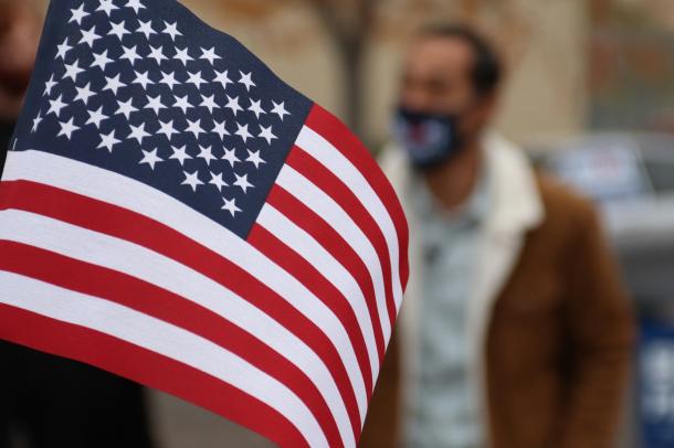 A large United States flag in front of an out-of-focus person