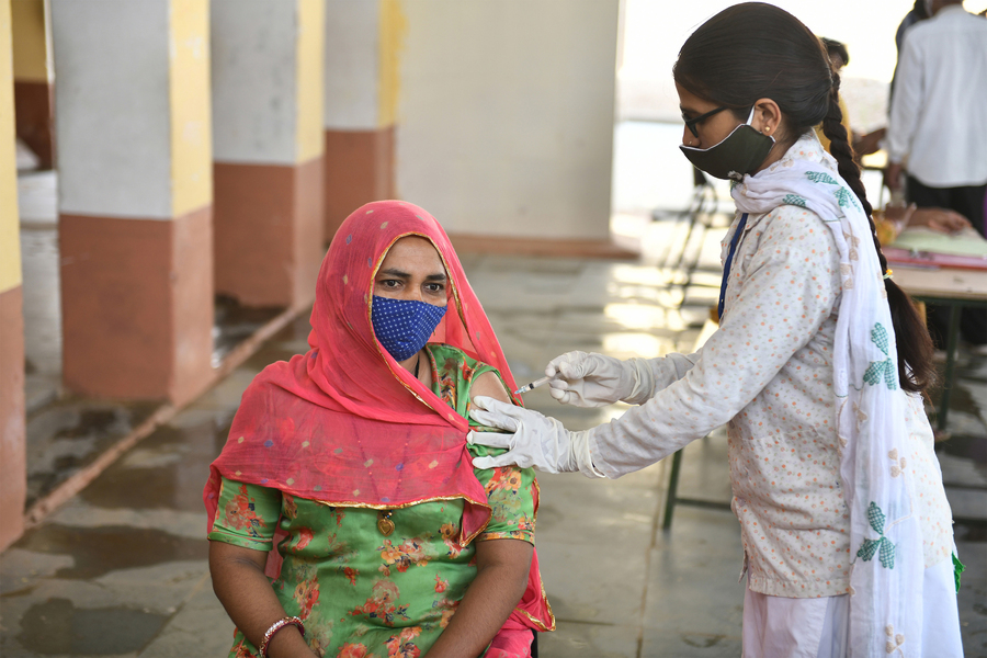 a doctor in India gives an injection to a patient in a sari