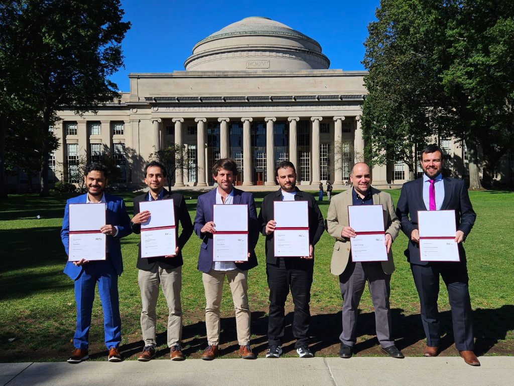 Learners hold their certificates in front of the MIT dome at Killian Court.
